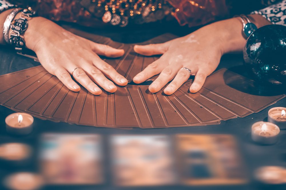 Fortune teller with tarot cards on table near burning candles.Tarot cards spread on table with crystal ball.Forecasting concept.