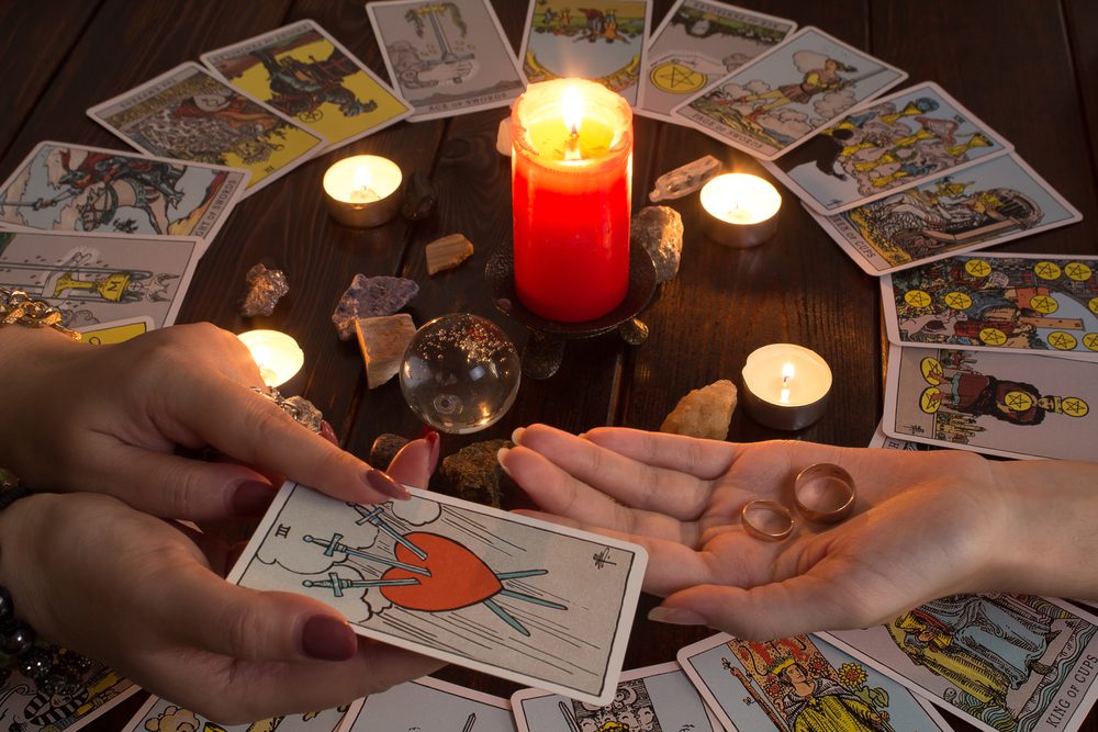 A person's hands holding a card next to a candle for love readings 