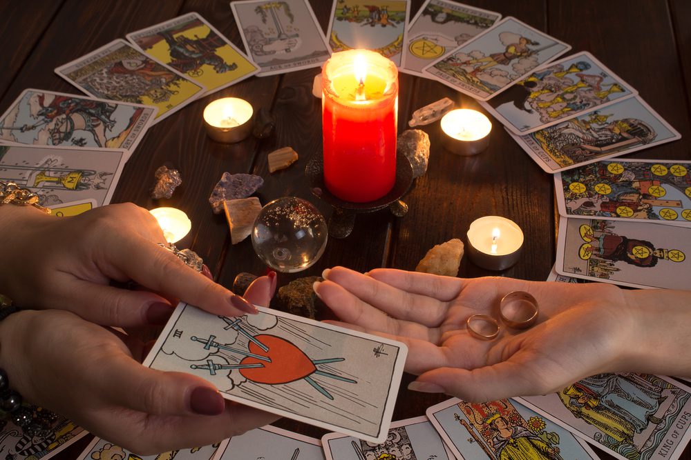 A person's hands holding a card next to a candle for love readings 